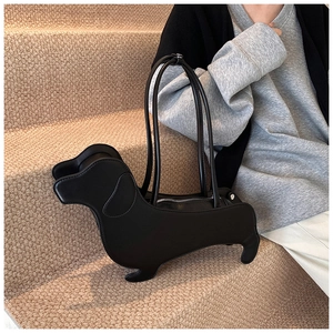 Unique dachshund-shaped black matte leather underarm tote bag on soft studio steps