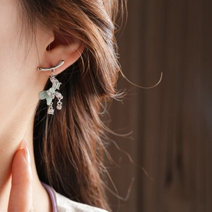 Detail of silver bow tassel earrings with green zircon stones worn on model
