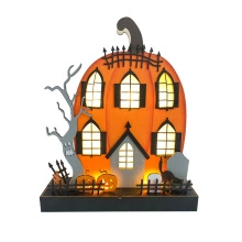 Close-up of glowing wooden Halloween pumpkin house with warm LED lights and black cat decor