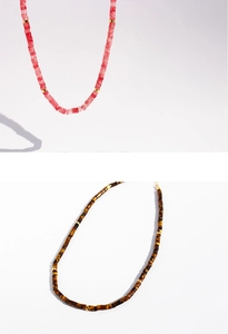 Macro shot of tiger eye and pink beads with golden spacers on a minimalist necklace