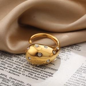 Close-up of a gold-plated teardrop ring with zircon stones on vintage book pages