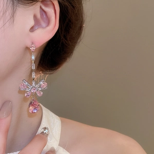 Detail of silver bow earrings with pink zircon tassels and pear-shaped drop crystals