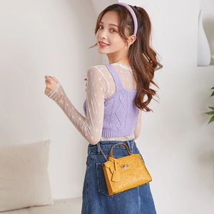 Detail of yellow embossed leather crossbody bag featuring cartoon patterns and chain strap