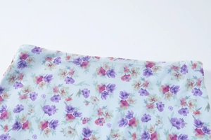 Detailed close-up of light blue floral mesh fabric with pink and purple flower patterns