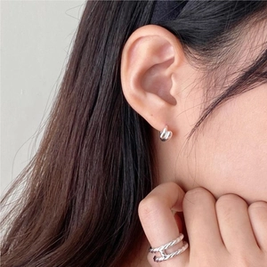 Detailed view of sterling silver teardrop earrings and a twisted ring worn by a model