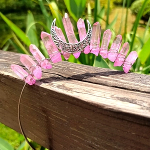 Detail of pink crystal moon crown with hand-wrapped metal wire on a wooden surface
