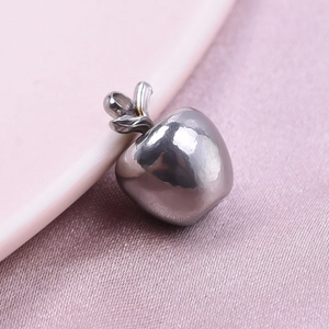 Detailed macro view of an apple shaped 304 stainless steel pendant on purple fabric