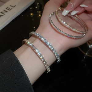 Detail of stacked gold and silver bracelets with sparkling row-set zircons on a model's wrist