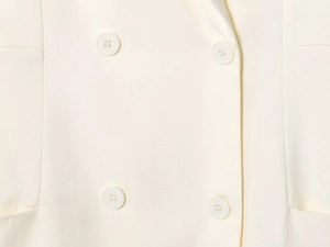 Macro shot of cream blazer with twill texture and double-breasted buttons detail