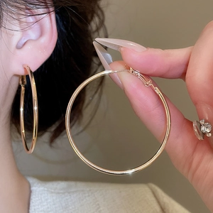 Close-up of polished gold large hoop earring with a sleek mirror finish on ear