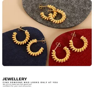 Detail of three pairs of gold twisted croissant hoop earrings on colorful felt pads