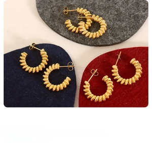 Detail of three pairs of gold twisted croissant hoop earrings on colorful felt pads