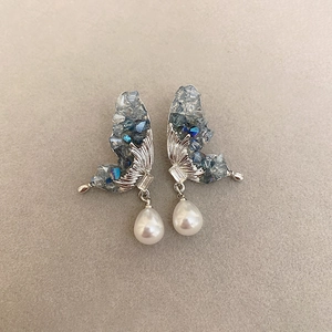 Detail of crystal butterfly earrings with silver plating and white teardrop pearls