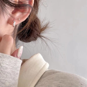 Close-up of minimalist 925 sterling silver twist hoop earrings and stud on model ear