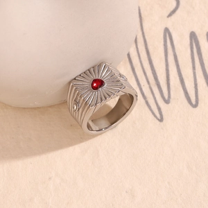 Macro shot of silver ring with red heart gemstone and radial pattern engraving