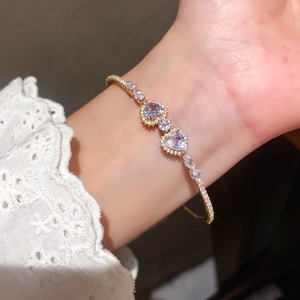 Detail of gold heart bangle featuring lavender crystals and pavé cubic zirconia