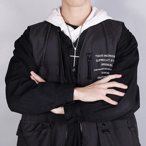 Pendentif croix en acier inoxydable argenté poli porté par un mannequin en gilet noir
