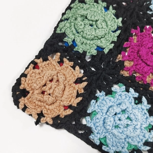 Macro shot of colorful handmade crochet granny square stitching with black yarn borders
