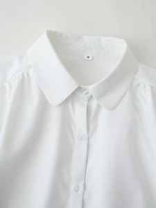 Detailed close-up of a white cotton shirt collar with buttons and a size S label