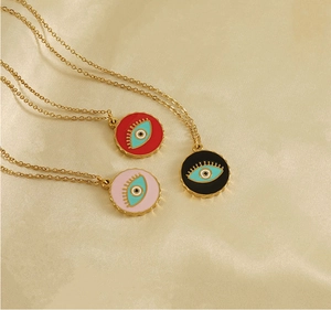 Close-up of gold stainless steel necklaces with red, pink, and black evil eye pendants