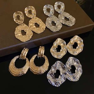 Detail of irregular textured geometric gold and silver metal earrings in a luxury gift box