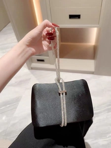 Detailed view of luxury black satin evening clutch bag with sparkling rhinestone handle