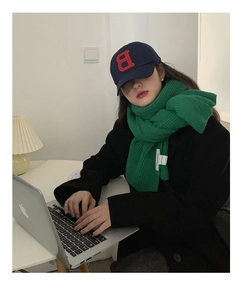 Detail of Mars green chunky knit scarf and navy blue baseball cap with red letter B embroidery