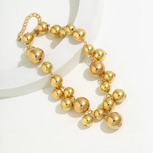 Macro detail of polished gold bead necklace featuring gradient spheres on white display
