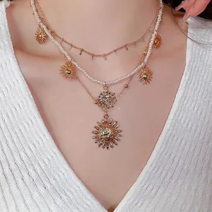 Elegant layered gold necklace featuring pearl strands and sun charms on a model