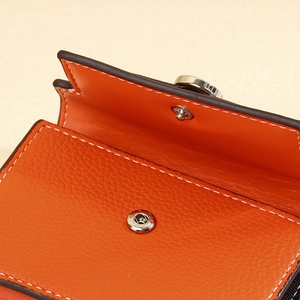 Macro view of orange litchi leather texture with white stitching and silver snap button