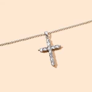 Minimalist silver cross necklace with sparkling rhinestones on a clean beige background