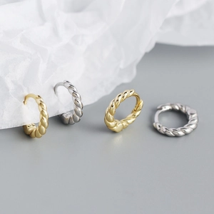 Detailed view of woven texture hoop earrings in gold and silver finishes on display