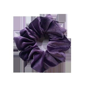 Donkerpaarse fluwelen scrunchie met zachte glans en geplooide textuur op witte achtergrond