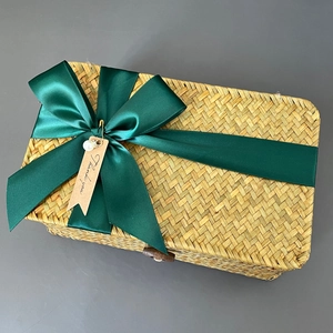 Macro detail of seagrass woven gift box featuring a green ribbon bow and Thank You tag