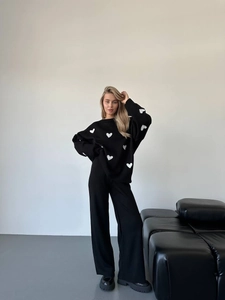 Dettaglio del ricamo a cuore e della trama in maglia su un maglione oversize nero