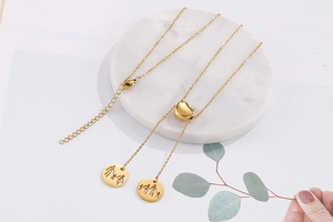 Detail of gold heart pendant necklace featuring family silhouette engravings on a white base