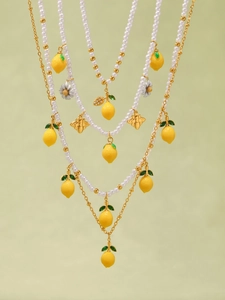 Dettaglio della collana di perle a strati con ciondoli a forma di limone, ape e margherita