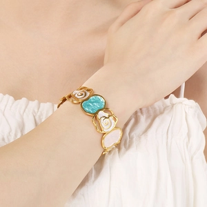 Detail of colorful enamel flower bangle on wrist with gold-plated stainless steel frame