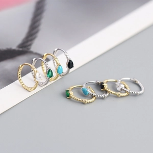 Macro shot of twisted hoop earrings in gold and silver with various colorful gemstones