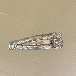 Dettaglio della molletta d'argento a spirale con orsetto di strass e cristallo quadrato lucido