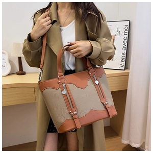 Close-up of brown and khaki leather tote bag with vertical zipper and buckle details