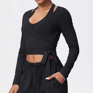 Detail of black long-sleeve yoga top featuring crossover wrap design and side bow tie