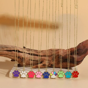 Detail of colorful cat paw enamel pendants with gold chains on a natural rustic background