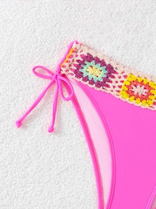 Close-up of pink bikini bottom with colorful handmade crochet flowers and side ties