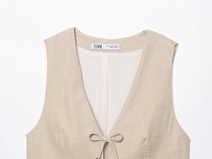 Detail of beige linen vest featuring delicate bow tie closure and textured fabric