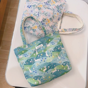 Gros plan de sacs cabas en toile à fleurs et lapins avec étiquettes Simple Wish