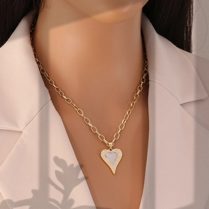 Close-up of a two-tone heart pendant necklace with zircon stones worn by a model