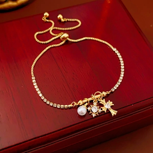 Détail de breloques croix dorée et perles sur un bracelet scintillant ajustable