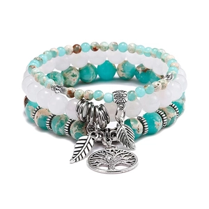 Detail of tree of life and leaf charms on four-layer turquoise beaded stretch bracelets