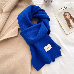 Detail of blue knitted scarf with small emo logo label showing thick soft texture